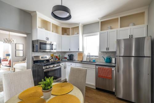 uma cozinha com armários brancos e um frigorífico de aço inoxidável em Red Robin Rentals - Wicker Park em Chicago