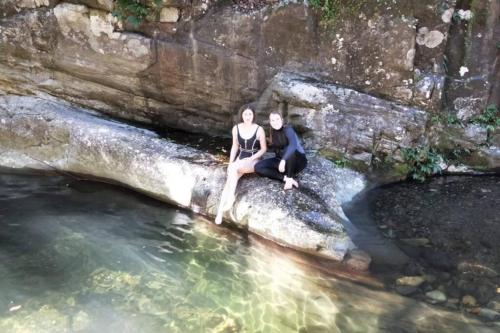 a man and woman sitting on a rock in the water at The Cabin Barrington Tops Your Eco Place in Nature in Chichester