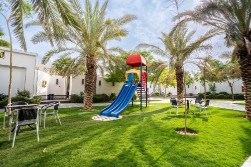 منتجع تاله  في الرياض: ملعب مع زحليقة في ساحة مع أشجار النخيل