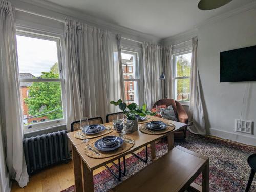 een woonkamer met een tafel, stoelen en ramen bij Sun-Kissed Sanctuary by Battersea Park in Londen