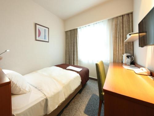 Habitación de hotel con cama y escritorio en Hotel Pearl City Morioka, en Morioka