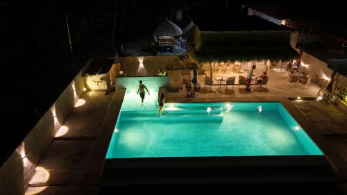 un hombre de pie en una piscina por la noche en Villa Alessandra Homestay en Moalboal