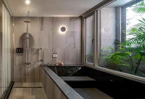 baño con bañera y ducha con ventana en Crownshine Resort, en Jiaoxi