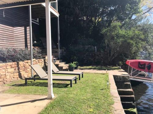 a group of benches sitting on the grass near the water at NINE at Berowra Waters, luxury waterfront with hot tub in Berrilee