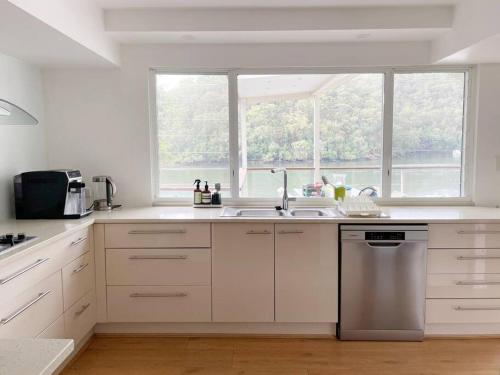a white kitchen with a sink and a window at NINE at Berowra Waters, luxury waterfront with hot tub in Berrilee