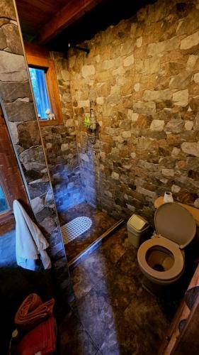 a stone bathroom with a toilet and a shower at Beehouse Mandala in Guarne