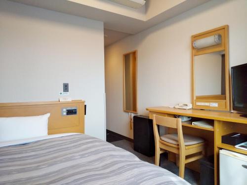 a hotel room with a bed and a desk with a computer at Hotel Route-Inn Sanofujioka Inter in Sano