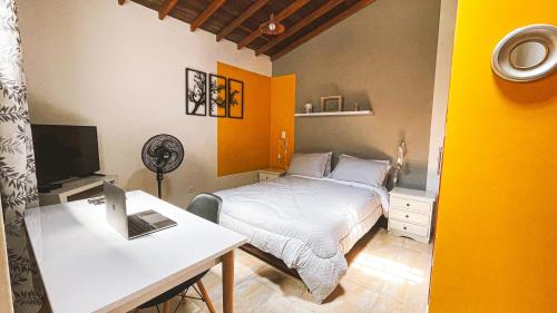 a bedroom with a bed and a desk with a computer at Malaika Hostel Medellín in Medellín