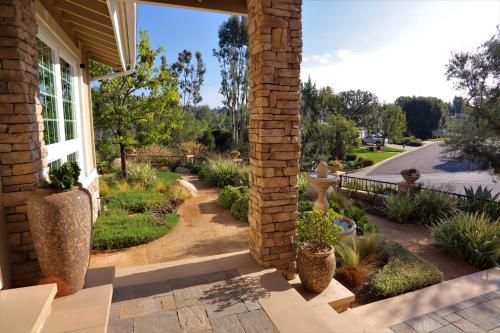 a brick house with a porch with potted plants at The Sanctuary in Laguna Hills