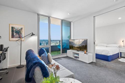 een woonkamer met een bed en een televisie bij Chic 1-Bed with Balcony Views and Amenities in Melbourne