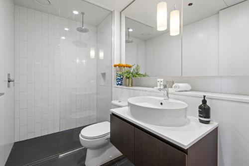 een witte badkamer met een wastafel en een toilet bij Chic 1-Bed with Balcony Views and Amenities in Melbourne