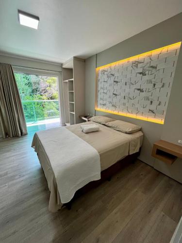 a bedroom with a large bed and a large window at Hotel Sítio Novo in Piratuba