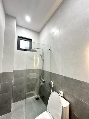 a bathroom with a toilet and a glass shower at Aboli Homestay in Phan Thiet