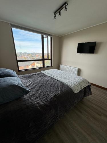 a bedroom with a large bed and a large window at PuertoVarasC101 in Puerto Varas