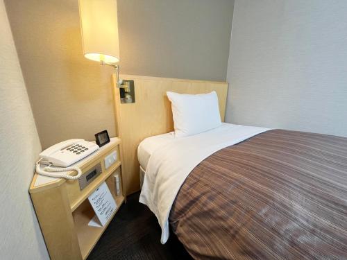 a hotel room with a bed and a telephone at Hotel Route-Inn Sapporo Ekimae Kitaguchi in Sapporo
