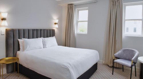 um quarto com uma cama grande e uma cadeira em The Metropole Guest House Katoomba em Katoomba