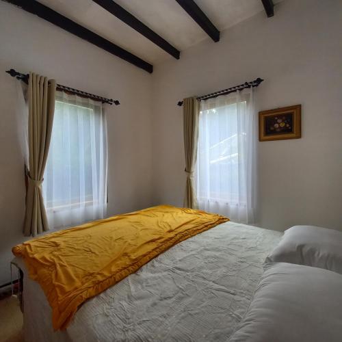 a bedroom with a bed with a yellow blanket on it at Chrysant Huis Villa Istana Bunga in Bandung