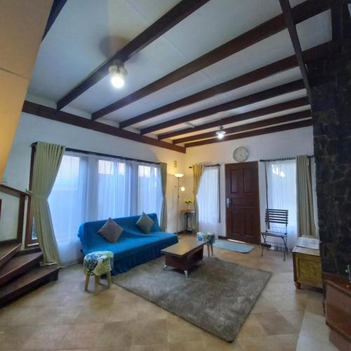 a living room with a blue couch and some windows at Chrysant Huis Villa Istana Bunga in Bandung