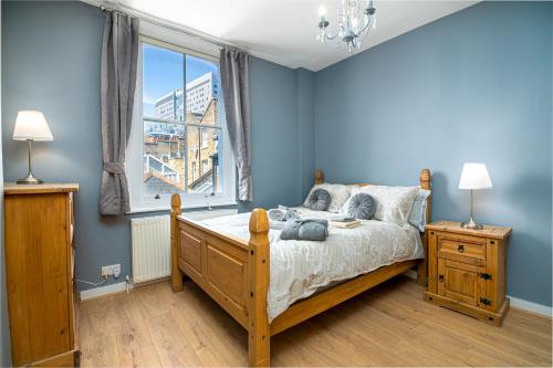 a bedroom with a bed with blue walls and a window at Fantastic House New Refurbished in London