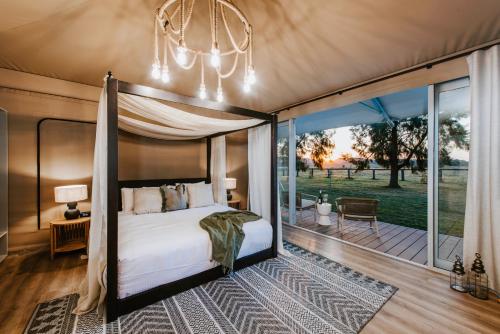 a bedroom with a canopy bed and a patio at Parklands Resort in Mudgee
