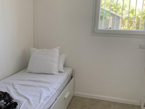 Cette chambre blanche dispose d'un lit et d'une fenêtre. dans l'établissement T2 Hyères : à 50m de la Plage, Proche du Port, Jardinet Privatif, Idéal Familles - FR-1-335-202, à Hyères