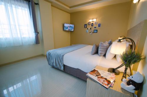 a bedroom with a bed and a table with a lamp at Thipurai City Hotel in Hua Hin