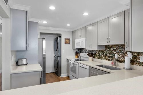 a kitchen with white cabinets and stainless steel appliances at St Kitts - Downtown Waterfront Penthouse Pool Dock Parking in Key West