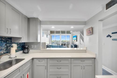 a kitchen with white cabinets and a sink and a window at St Kitts - Downtown Waterfront Penthouse Pool Dock Parking in Key West