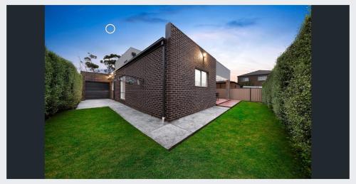 una casa de ladrillo con un césped verde delante de ella en Modern Masterpiece Beautiful St Albans 4BR Home, en Ardeer