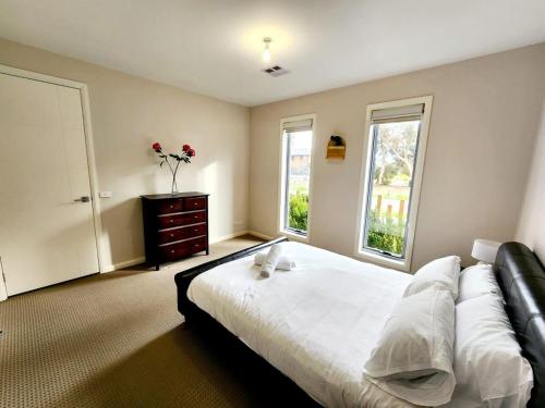 Un dormitorio con una cama grande y dos ventanas. en Modern Masterpiece Beautiful St Albans 4BR Home, en Ardeer