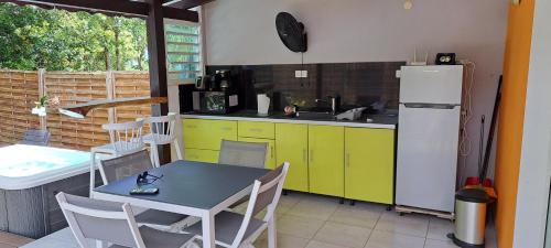 a kitchen with a table and yellow cabinets and a refrigerator at Rêve créole in Deshaies