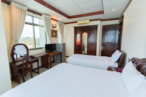 a hotel room with two beds and a desk at Phúc Đạt Hotel in Vung Tau