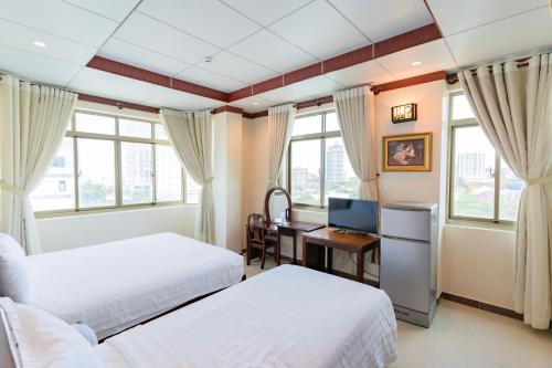 a bedroom with two beds and a desk with a computer at Phúc Đạt Hotel in Vung Tau