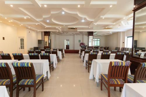 um salão de banquetes com mesas e cadeiras brancas em Phúc Đạt Hotel em Vung Tau