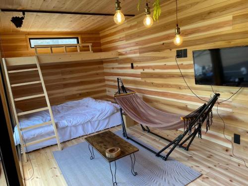 a hammock in a log cabin with a tv and a bed at Lulu in Minami Alps