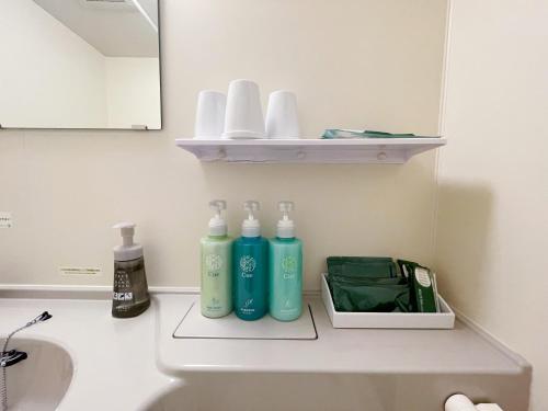 a bathroom with three bottles of soap and a mirror at Hotel Route-Inn Fujieda-Eki Kita in Fujieda