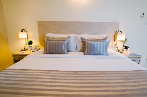 a bedroom with a large bed with pillows and two lamps at Thipurai City Hotel in Hua Hin
