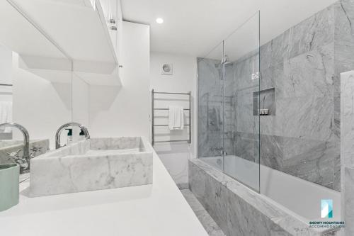 a white bathroom with a sink and a shower at Deadwood Den - Luxurious 3BR Townhouse l Lake Views l Bath l WiFi in Jindabyne