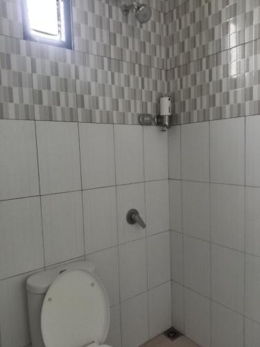 a white bathroom with a toilet and a window at The New Orlinds Guest House in Wonosari
