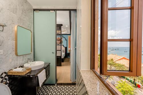 a bathroom with a sink and a mirror and a window at Hoàng Hôn Tím Boutique Hotel in Phú Quốc
