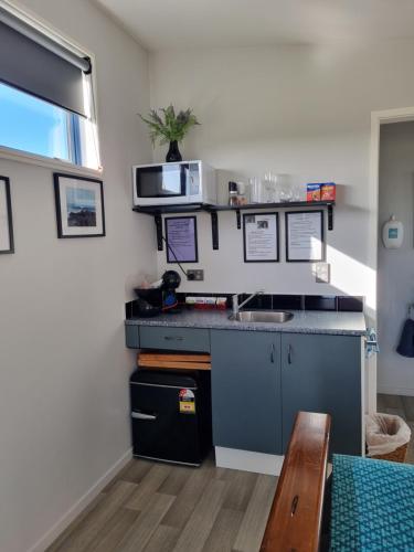 eine Küche mit einer Spüle und einer Mikrowelle in der Unterkunft Denchys B&B in Matamata