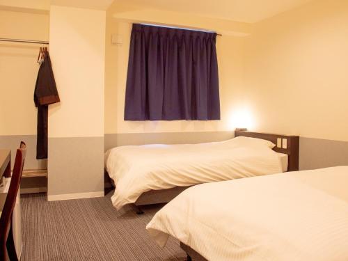 松山市にあるホテルたいよう農園 二番町のベッド2台と窓が備わるホテルルームです。