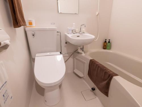 a white bathroom with a toilet and a sink at Hotel Taiyo Noen Nibancho in Matsuyama