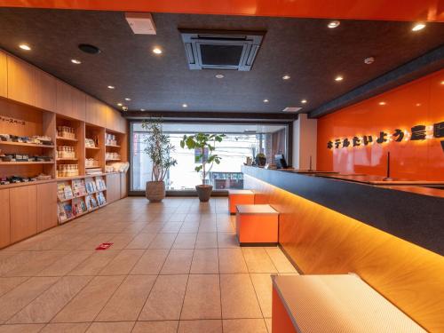 a restaurant with orange walls and a bar with benches at Hotel Taiyo Noen Nibancho in Matsuyama