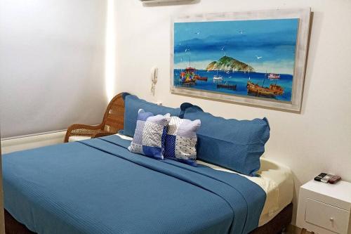 a bedroom with a blue bed with a painting on the wall at ESPECTACULAR APARTAMENTO EN SAMARIA CLUB DE PLAYA smr in Gaira