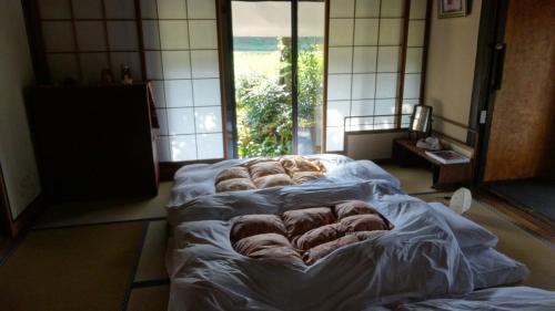 um quarto com três camas num quarto com uma janela em 古民家の宿 ふるま家 Furumaya House Gastronomic Farmstay in Deep Kyoto em Fukuchiyama