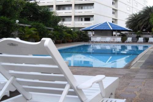 a white lounge chair sitting next to a swimming pool at 2 Somphong Ban Amphur Beach Thailand Condotel in Na Jomtien