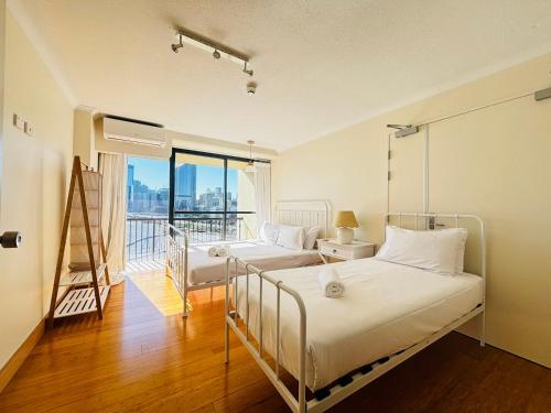 Un dormitorio con dos camas y un balcón. en River Plaza Apartments Brisbane Southbank, en Brisbane