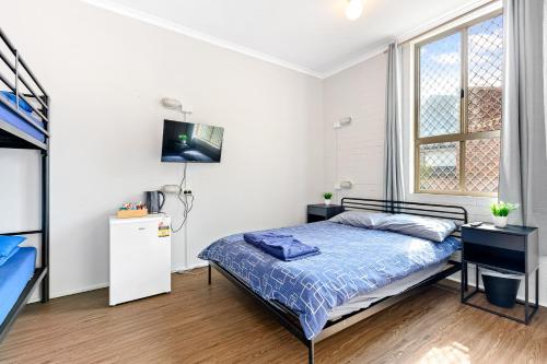 a bedroom with a bed and a tv on a wall at Newtown Backpackers in Sydney