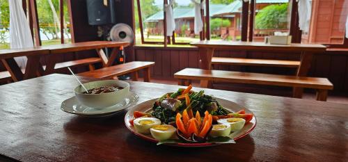 a plate of vegetables and eggs on a wooden table at Raflow Resort Raja Ampat in Tapokreng